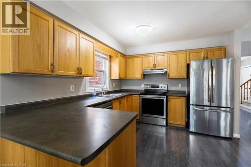 Kitchen featuring wood-finish cabinetry, dark countertops, stainless steel appliances, and dark wood-finish flooring - 248 Bridlewreath Street, Kitchener, ON - Indoor Photo Showing Kitchen With Double Sink
