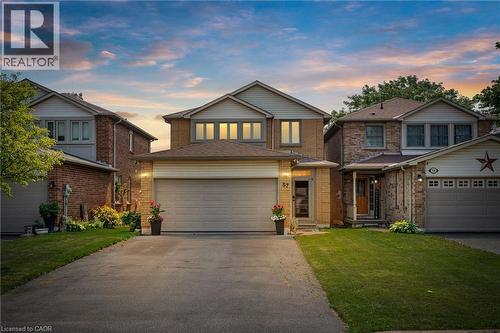 Brick and siding exterior featuring a two-car garage, driveway, and an entryway with a covered porch - 57 Grindstone Way, Waterdown, ON - Outdoor With Facade