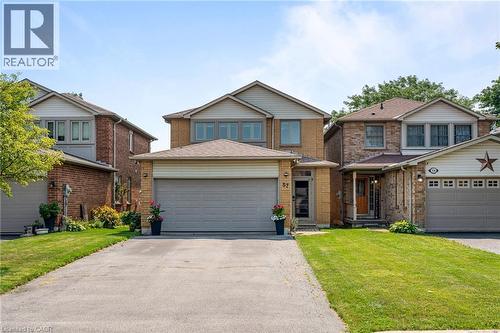 Brick facade with light-colored siding accents, attached two-car garage, paved driveway, and covered front entry - 57 Grindstone Way, Waterdown, ON - Outdoor With Facade