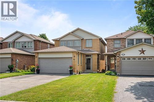 Brick exterior with siding accents, attached garage, paved driveway, and manicured front lawn - 57 Grindstone Way, Waterdown, ON - Outdoor With Facade