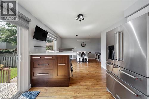 Hardwood-style flooring throughout, stainless steel refrigerator, kitchen island with wood cabinetry, and sliding glass door - 57 Grindstone Way, Waterdown, ON - Indoor