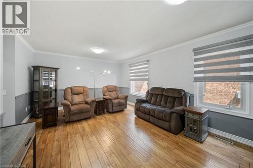 Hardwood flooring, crown molding, two-tone wall treatment, and multiple windows - 57 Grindstone Way, Waterdown, ON - Indoor Photo Showing Living Room