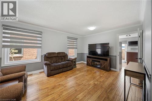 Wood-finish flooring, two-tone wall treatment, crown molding, windows with blinds, and flush mount lighting - 57 Grindstone Way, Waterdown, ON - Indoor Photo Showing Living Room
