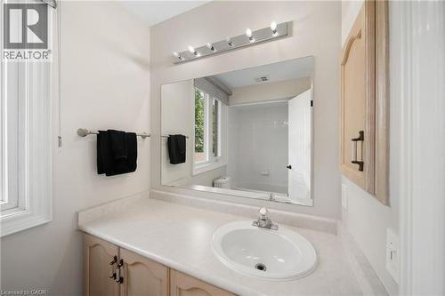 Vanity with integrated sink, expansive mirror, and overhead strip lighting - 57 Grindstone Way, Waterdown, ON - Indoor Photo Showing Bathroom