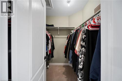 Walk-in closet with carpet flooring, white painted shelving, and a single ceiling light fixture - 57 Grindstone Way, Waterdown, ON - Indoor With Storage