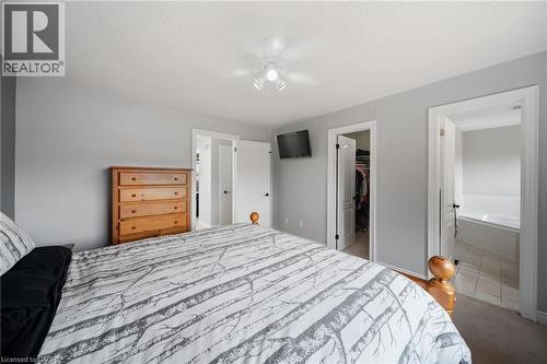 Wall-mounted lighting fixture, light gray wall color, white interior doors, built-in closet, and a white soaking tub - 57 Grindstone Way, Waterdown, ON - Indoor Photo Showing Bedroom