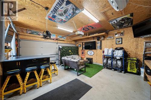 Finished garage with a built-in bar, overhead garage door, and a dedicated seating area with artificial turf flooring - 57 Grindstone Way, Waterdown, ON - Indoor Photo Showing Garage