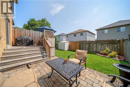 Brick exterior featuring a wooden deck with stairs, a paver patio, a fenced yard, and a storage shed - 57 Grindstone Way, Waterdown, ON - Outdoor With Deck Patio Veranda With Exterior