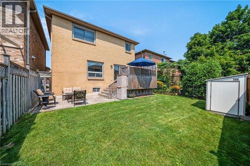 Expansive green lawn with a patio area, privacy fencing, and an exterior storage shed - 57 Grindstone Way, Waterdown, ON - Outdoor With Exterior