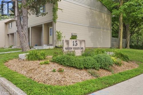 Exterior featuring siding, mature trees, a stone address marker, and landscaped garden beds with wood chip mulch - 15 Green Valley Drive Unit# 41, Kitchener, ON - Outdoor