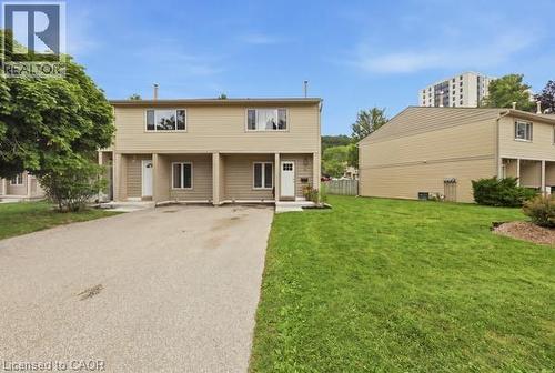 Two-story residence with beige siding, white trim windows, and individual entry doors - 15 Green Valley Drive Unit# 41, Kitchener, ON - Outdoor With Deck Patio Veranda