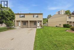 Two-story residence with beige siding, white trim windows, and individual entry doors - 