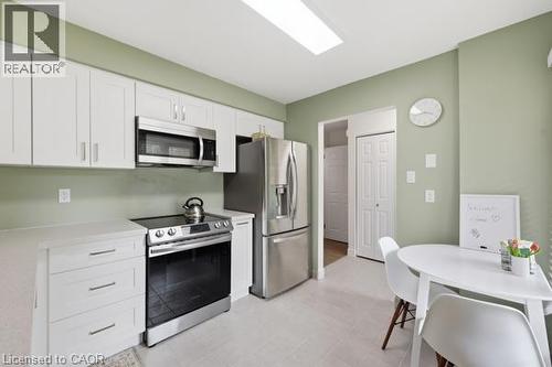 Kitchen featuring white cabinetry, stainless steel appliances, a flush-mounted ceiling light fixture, and light-toned tile flooring - 15 Green Valley Drive Unit# 41, Kitchener, ON - Indoor Photo Showing Kitchen