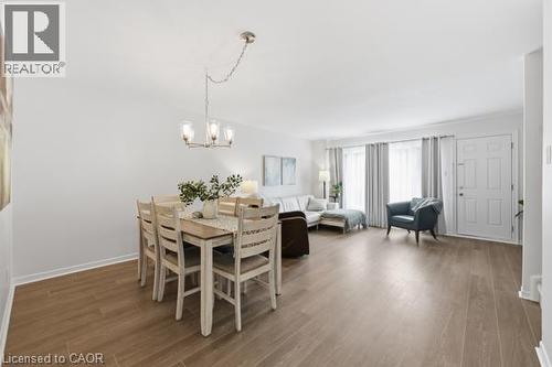 Open concept living area featuring wood-finish flooring, a contemporary chandelier, and a white paneled entry door - 15 Green Valley Drive Unit# 41, Kitchener, ON - Indoor Photo Showing Dining Room