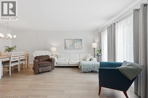 Wood-finish flooring throughout, light-toned walls, and an overhead chandelier with clear glass shades - 15 Green Valley Drive Unit# 41, Kitchener, ON - Indoor Photo Showing Living Room