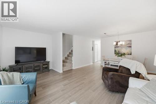 Wood-finish flooring throughout, bright white walls, recessed staircase with carpeted treads, and a dining area featuring a chandelier - 15 Green Valley Drive Unit# 41, Kitchener, ON - Indoor Photo Showing Living Room