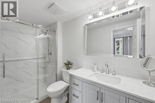 Glass-enclosed shower with white marble-look paneling, light gray vanity with white countertop, chrome faucet, and rectangular framed mirror with vanity lighting - 15 Green Valley Drive Unit# 41, Kitchener, ON - Indoor Photo Showing Bathroom
