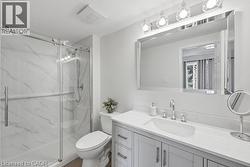 Glass-enclosed shower with white marble-look paneling, light gray vanity with white countertop, chrome faucet, and rectangular framed mirror with vanity lighting - 