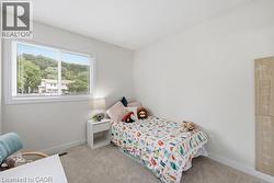 Bright room featuring a large window with white blinds, light-toned walls, and grey carpeting - 