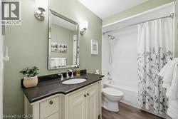 Bathroom featuring a vanity with dark countertop, undermount sink, and chrome fixtures - 
