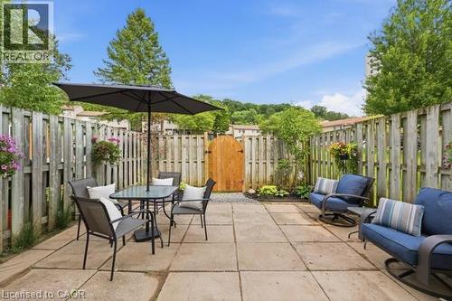 Fenced patio with square paver stones, a wooden gate, and perimeter landscaping - 15 Green Valley Drive Unit# 41, Kitchener, ON - Outdoor With Deck Patio Veranda