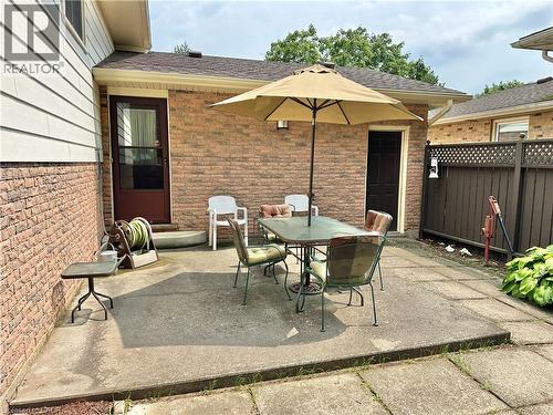 Expansive concrete patio area with a privacy fence and exterior brick walls - 44 Douglas Avenue, Simcoe, ON - Outdoor With Exterior