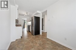 Kitchen featuring white cabinetry, stone-finish countertops, tile flooring, and stainless steel appliances - 