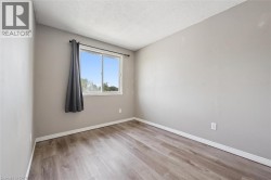 Wood-finish flooring, neutral wall color, and a window with a white frame - 