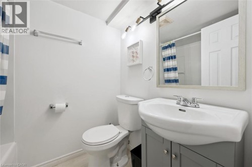 Clean and functional bathroom featuring a curved pedestal sink with chrome faucet, mirrored medicine cabinet, white cabinetry with storage, and ceramic tile flooring - 750 Erinbrook Drive Unit# 2, Kitchener, ON - Indoor Photo Showing Bathroom