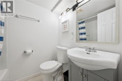 Clean and functional bathroom featuring a curved pedestal sink with chrome faucet, mirrored medicine cabinet, white cabinetry with storage, and ceramic tile flooring - 