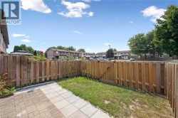 Private backyard featuring a wood fence, a paved patio, and a grass area - 