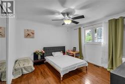 Hardwood-finish flooring, white walls, ceiling fan with light fixture, double window, and crown molding - 