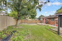 Expansive backyard featuring a large mature tree, wood fencing, and a brick-faced exterior - 