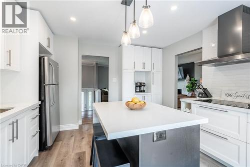 Kitchen featuring white cabinetry, wood-finish flooring, a central island with a light-colored countertop, stainless steel appliances, and a range hood - 152 Concession 7 Road E, Millgrove, ON - Indoor Photo Showing Kitchen With Upgraded Kitchen