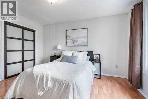 Wood-finish flooring, sliding closet doors with frosted panels, ceiling-mounted light fixture, and a window with a curtain rod - 152 Concession 7 Road E, Millgrove, ON - Indoor Photo Showing Bedroom