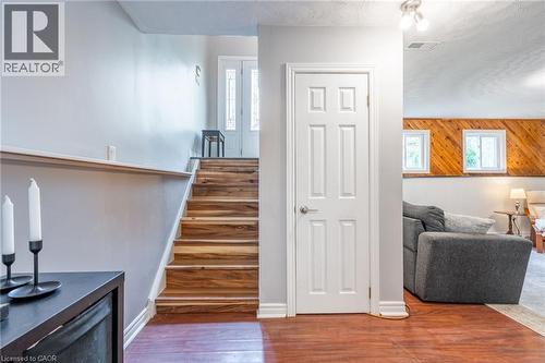 Wood-finish flooring, staircase with wood treads, white panel door, white trim, and two square windows with wood paneling - 152 Concession 7 Road E, Millgrove, ON - Indoor Photo Showing Other Room