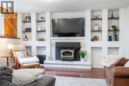 Sophisticated living room anchored by a custom built-in entertainment center featuring white brick surround, integrated shelving with display niches, and a gas fireplace insert - 152 Concession 7 Road E, Millgrove, ON - Indoor Photo Showing Living Room With Fireplace