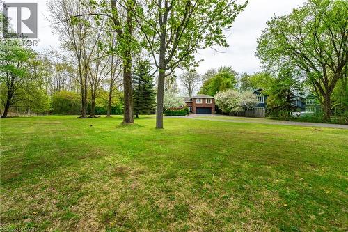 Expansive lawn area with mature trees and a paved driveway leading to the brick exterior and attached garage - 152 Concession 7 Road E, Millgrove, ON - Outdoor