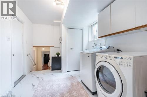 Laundry area with a front-loading washing machine, top-loading washing machine, wall-mounted cabinetry, and a window - 152 Concession 7 Road E, Millgrove, ON - Indoor Photo Showing Laundry Room