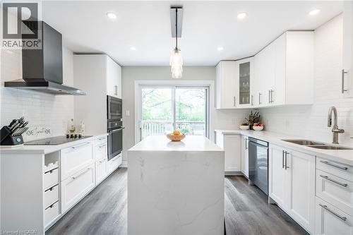 Contemporary kitchen featuring white cabinetry, a large center island, integrated stainless steel appliances, and wood-finish flooring - 152 Concession 7 Road E, Millgrove, ON - Indoor Photo Showing Kitchen With Double Sink With Upgraded Kitchen