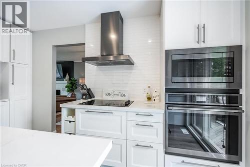 White shaker cabinetry with brushed nickel hardware, stainless steel wall-mounted range hood, built-in microwave, integrated wall oven, and white subway tile backsplash - 152 Concession 7 Road E, Millgrove, ON - Indoor Photo Showing Kitchen With Upgraded Kitchen