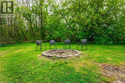 Expansive green lawn with a circular stone-edged fire pit, surrounded by mature trees - 152 Concession 7 Road E, Millgrove, ON - Outdoor
