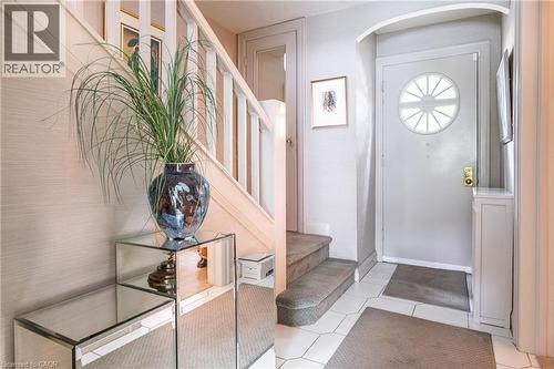 Entryway featuring a decorative front door with a radial window, white hexagonal floor tiles, and a staircase with white wood balusters and carpeted treads - 107 Bond Street S, Hamilton, ON - Indoor Photo Showing Other Room