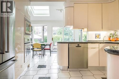 Kitchen featuring light-toned cabinetry, stainless steel dishwasher, and dark countertops - 107 Bond Street S, Hamilton, ON - Indoor Photo Showing Other Room