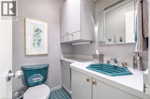 Wall-mounted upper cabinetry, a coordinating vanity with a white countertop, and a uniquely shaped blue basin - 107 Bond Street S, Hamilton, ON - Indoor Photo Showing Bathroom