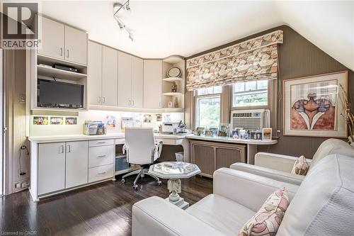 Built-in cabinetry with under-cabinet lighting, rich wood-finish flooring, track lighting, and a window with custom window treatments - 107 Bond Street S, Hamilton, ON - Indoor