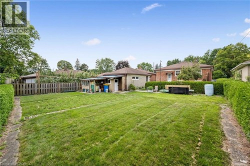 Expansive rear grounds featuring a meticulously manicured lawn with mature tree-lined perimeter, brick paver pathways, and established hedging - 133 Emma Street, Guelph, ON - Outdoor