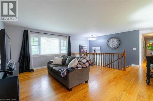 Bright living area featuring wood-finish flooring, a large multi-pane window, and a wood railing - 111 Decou Road, Simcoe, ON - Indoor Photo Showing Living Room