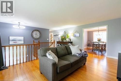 Hardwood flooring extending throughout the space, featuring a wood spindle railing, an open concept to another room, and a contemporary ceiling light fixture - 111 Decou Road, Simcoe, ON - Indoor Photo Showing Living Room