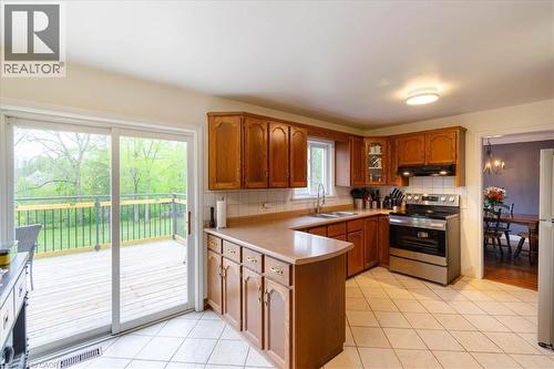 Kitchen featuring wood cabinetry, stainless steel range, and tile flooring - 111 Decou Road, Simcoe, ON - Indoor Photo Showing Kitchen With Double Sink